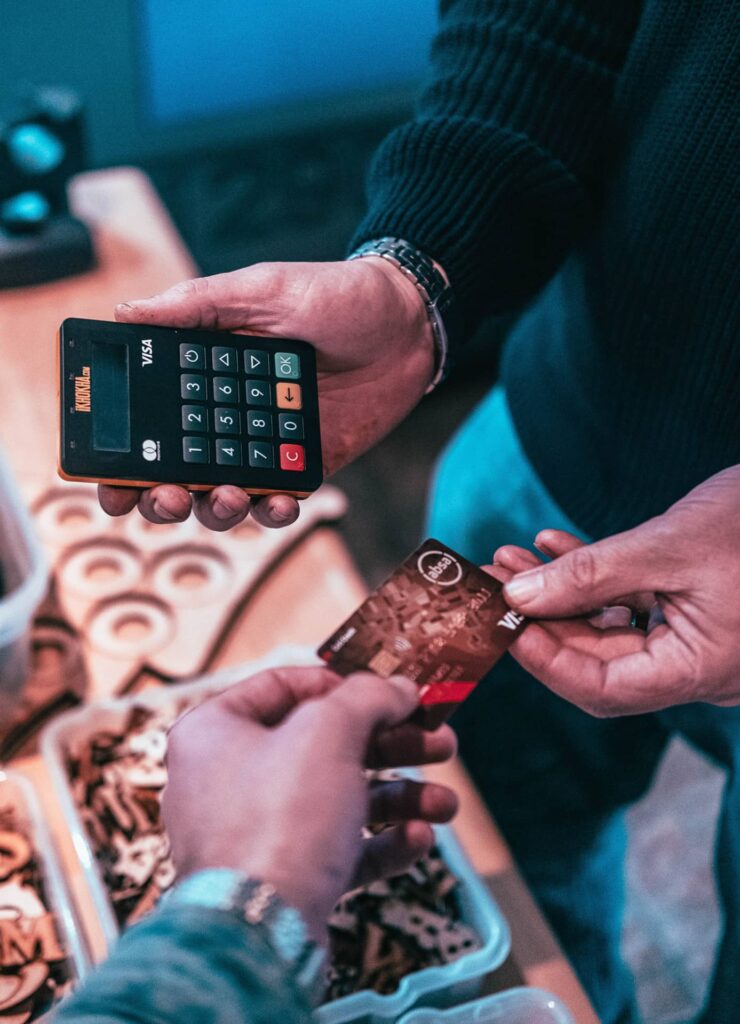 A close-up of two people exchanging payments with a credit card and calculator